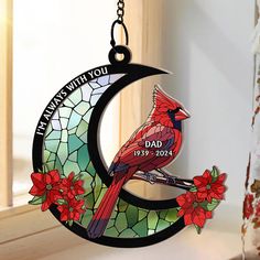 a stained glass christmas ornament with a cardinal sitting on the moon and flowers