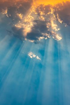 the sun is shining through clouds with blue sky and yellow light coming from behind it