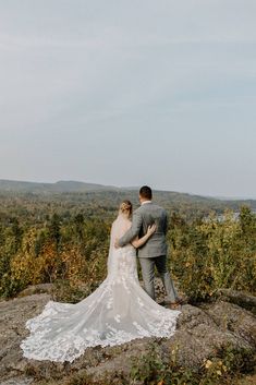 a bride and groom standing on top of a mountain