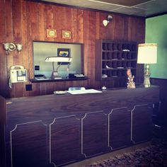 a large wooden counter sitting in the middle of a room with a lamp on top of it