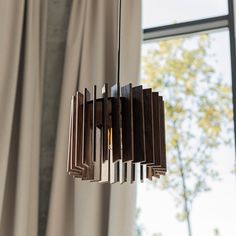 a wooden chandelier hanging from the ceiling in front of a window with curtains