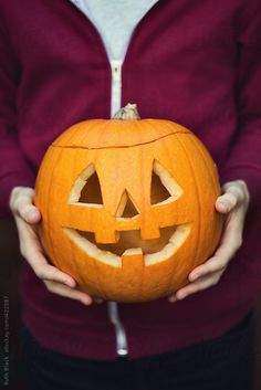 a person holding a carved pumpkin in their hands