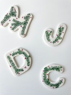 three ceramic letters decorated with christmas greenery