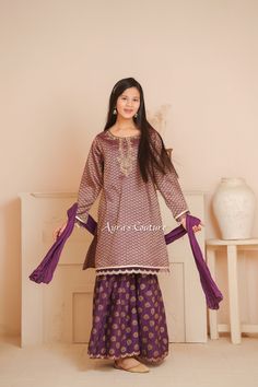 Ready to wear 3 pc Formal suit. A rich purple and gold jacquard kameez with exquisite hand adda work touches on the neckline and gold lace trimmings on the sleeves and daman. Accompanied with a purple cotton gharara with an interesting gold print to give a refreshing style to the silhouette. The purple crush dupatta completes this mesmerizing three piece suit and is sure to keep your doll en vogue this shaadi season. Item Details: Top: Purple Cotton Jacquard Kurta With Hand Adda Work and Lace Work Bottom: Purple Cotton Gharara with Print Dupatta: Purple Crush Dupatta Feel free to ask about the measurements. We are happy to help you. Thank you.. * As it is handmade, some stones or threads may be pulled off. We really do take great care of our clothes while shipping. Thank you.. **All sales Anarkali Purple Palazzo Set With Gota Work, Traditional Drape Purple Palazzo Set With Dabka Work, Traditional Purple Palazzo Set With Zari Work, Festive Purple Palazzo Set With Pallu, Festive Purple Kurta With Gota Work, Festive Purple Palazzo Set With Zari Work, Diwali Purple Palazzo Set With Traditional Drape, Festive Purple Palazzo Set With Dupatta, Traditional Purple Kurta With Gota Work