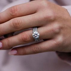 a woman's hand with a diamond ring on top of her finger and the other hand holding an engagement ring