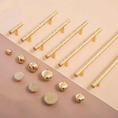 the gold studs are next to each other on a pink surface and there is an assortment of them