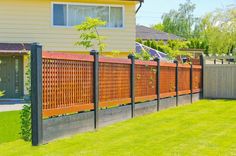 a house with a fence in front of it and green grass on the ground next to it