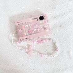 a pink phone case sitting on top of a white bed next to a lanyard