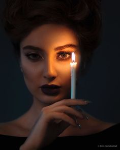 a woman holding a candle in front of her face