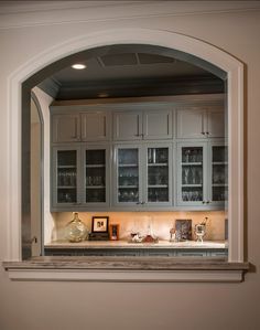 an arched window in a kitchen filled with cabinets