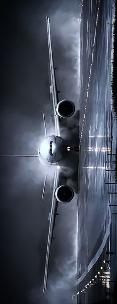 an airplane that is flying in the sky over some water and buildings at night time