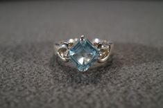 I am offering you this vintage sterling silver Art Deco style band ring with a gorgeous prong set trillion triangle shaped, genuine blue topaz stone. There is a regal influence in the design here, very nice! There is fabulous design setting. It measures app. 3/4 inch, by app. 1/4 inch. It has color saturation and intensity that is endless, as seen in the provided pictures. What an eye catcher! It has the classic highly desired solid setting that is very thick and substantial, giving this ring al Formal Trillion Cut Topaz Ring In Fine Jewelry Style, Formal Trillion Cut Topaz Fine Jewelry Ring, Silver Blue Topaz Ring With Diamond Cut, Elegant Trillion Cut Topaz Diamond Ring, Elegant Trillion Cut Topaz Ring, Elegant Trillion Cut Topaz Promise Ring, Fine Jewelry Topaz Ring With Trillion Cut, Fine Jewelry Trillion Cut Topaz Ring, Fine Jewelry Topaz Ring With Trillion Cut Gemstone