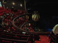 an auditorium filled with people and red seats