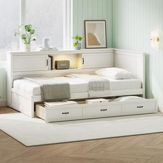 a bed with two drawers underneath it in a room that has green walls and hardwood floors