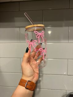 a person holding up a glass with pink bows on it and a straw in the bottom