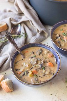 two bowls filled with soup next to bread