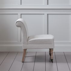 a white chair sitting on top of a hard wood floor in front of a wall