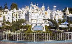 a large white castle with lots of trees and bushes around it's perimeter in front of a fence