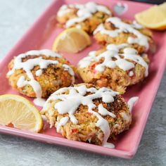 three crab cakes on a pink plate with lemon wedges