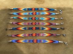 five beaded bracelets are lined up on the ground, each with different colors and designs