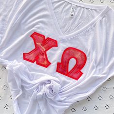 a white t - shirt with red letters on it and a knot at the bottom