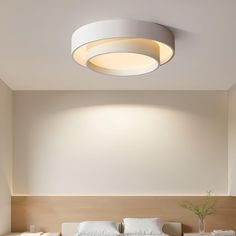 a white bed sitting under a round light in a bedroom