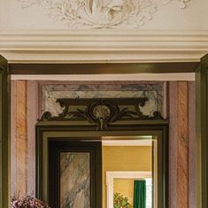 an ornate doorway leading into a room with green curtains and flowers on the ledges