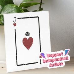 a card with a heart and crown on it sitting next to a potted plant