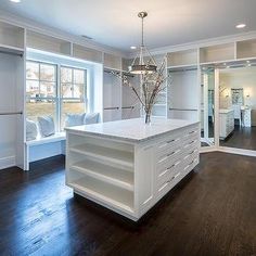 a large open concept kitchen with white cabinets and wood flooring, along with an island in the middle