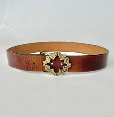 "A vintage belt circa 1970s made in thick and sturdy warm brown leather. Cute heavy weight brass buckle with brutalist style abstract hearts design. Bucked can be removed, band has a snap closure. Buckle loops though and attached with prong on adjustable holes. Perfect worn on the hip with jeans or at the waist. Marked: stamp on band is illegible, buckle reads slid brass but no signature Best fits size: Large  depending on how you wear it. Please see measurements to be sure! Can fit 36-39\" wais Artisan Brown Belt With Antique Buckle, Brown Artisan Belt With Antique Buckle, Artisan Brown Belt Buckle With Belt Included, Vintage Distressed Brown Belt Buckles, Vintage Adjustable Distressed Brown Belt Buckles, Vintage Antique Buckle Belt In Distressed Brown, Vintage Brown Belt Buckle With Antique Detail, Vintage Gold Leather Belt Buckles, Vintage Brown Belt Buckles With Brass Buckle