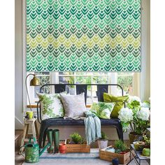 a living room with green and white patterned roman shades on the windowsill, potted plants in front of the window