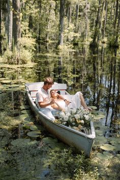 a man and woman in a boat on the water with lily paddling around them