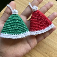 two small crocheted christmas ornaments are held in someone's hand on a table