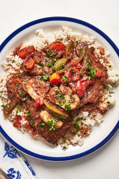 a white plate topped with rice and meat next to a fork on top of a table