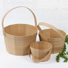 three brown paper baskets sitting next to each other on a white surface with green plants