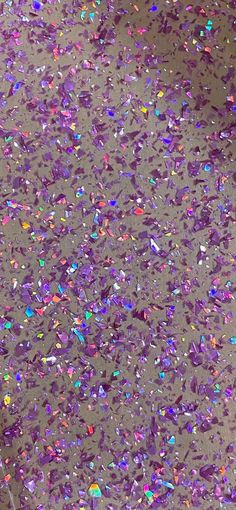 a large group of confetti on top of a gray surface with lots of colored sprinkles