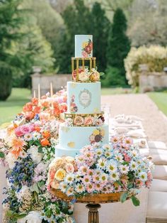 a three tiered cake sitting on top of a table covered in lots of flowers