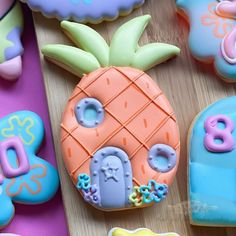 decorated cookies are sitting on a table with letters and pineapples in the background