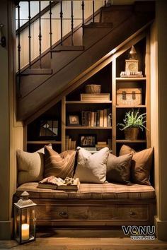 a couch sitting under a stair case next to a book shelf with books on it