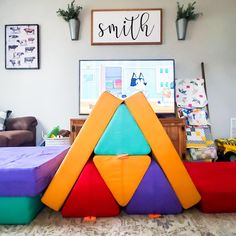 there is a large colorful pyramid in the middle of this room with other toys on the floor