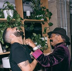 two men standing next to each other with plants in their hands and one man looking up