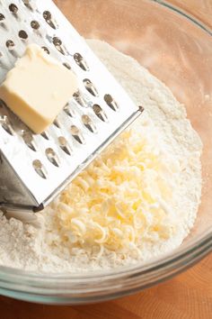 a bowl filled with flour and butter next to a grater