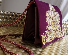 "Spectacular hand embroidered velvet clutch, using gold and frosted colored metallic threads, and semi precious stones, in the zardozi tradition. Genuine semi-precious stones sewn into the center of each flower. On lush, rich maroon colored velvet - a deep crimson red with brown and purple undertones. Gorgeous bag! Like a perfect little jewel box. Meticulous craftsmanship and detail. Measures 5.5 \" H x 8 \" W x 2.5 \" D. Room for your phone, credit cards, money, and makeup. Interior fully lined Festival Clutch With Gold Embroidery As Gift, Traditional Clutch With Gold Embroidery As Gift, Traditional Gold Embroidery Clutch As Gift, Festive Gold Embroidery Clutch As Gift, Gold Clutch With Floral Embroidery For Gift, Traditional Embroidered Velvet Clutch, Traditional Gold Embroidered Pouch Clutch, Traditional Rectangular Potli Bag With Gold Embroidery, Traditional Gold Embroidery Pouch Clutch