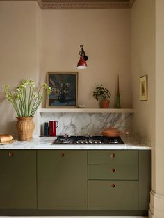 a kitchen with green cabinets and marble counter tops, including a stove top oven in the center