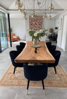 a dining room table with blue chairs and a vase on top of it in front of a large glass door