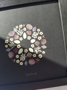 an image of a wreath made out of flowers on a black framed piece of paper