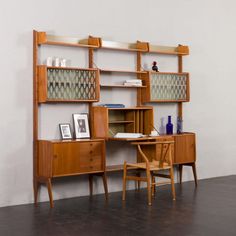 a wooden desk and chair in front of a book shelf with shelves on the wall