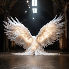 a large white bird with wings spread out in an old building, lit by spotlights from the ceiling