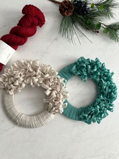 three yarn wreaths on a table with pine cones