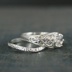 two silver rings with filigrees on them sitting on a table next to each other